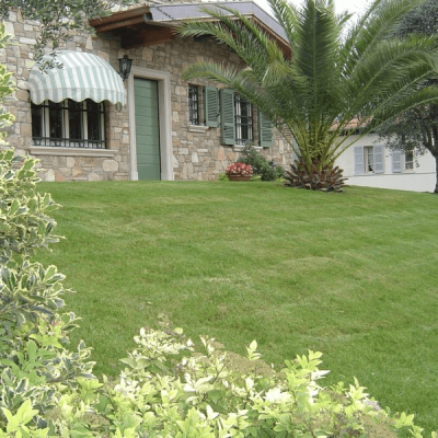 Giardino con prato a strisce davanti a una villa in pietra